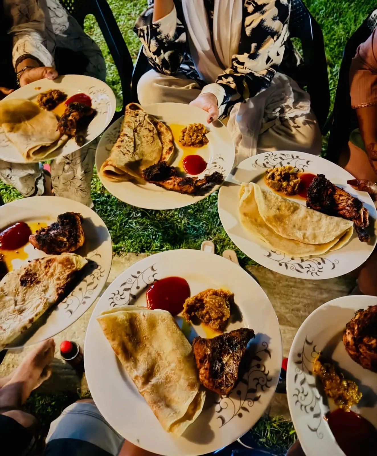 Plates of barbecue chicken and paratha on the lawn