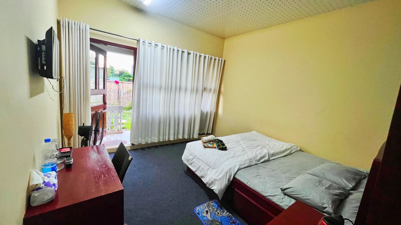 A guest room with a double bed and a window onto the veranda